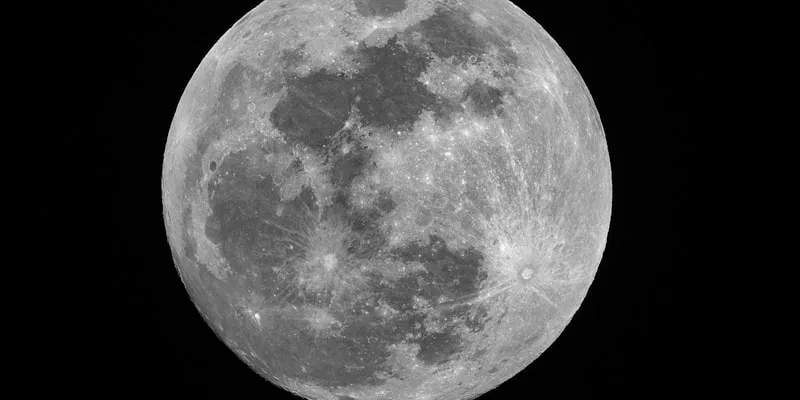 A luminous full moon rising over a calm dark ocean at twilight